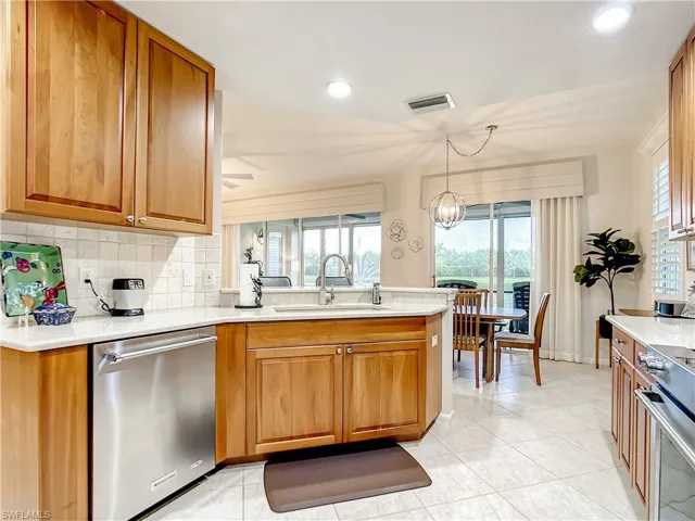 Kitchen featuring beautiful real wood cherry cabinets, quartz countertops, stone backsplash and stainless steel appliances.