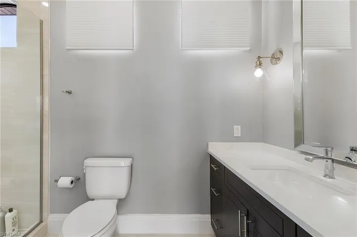 Bathroom featuring vanity, toilet, an enclosed shower, and tile patterned flooring