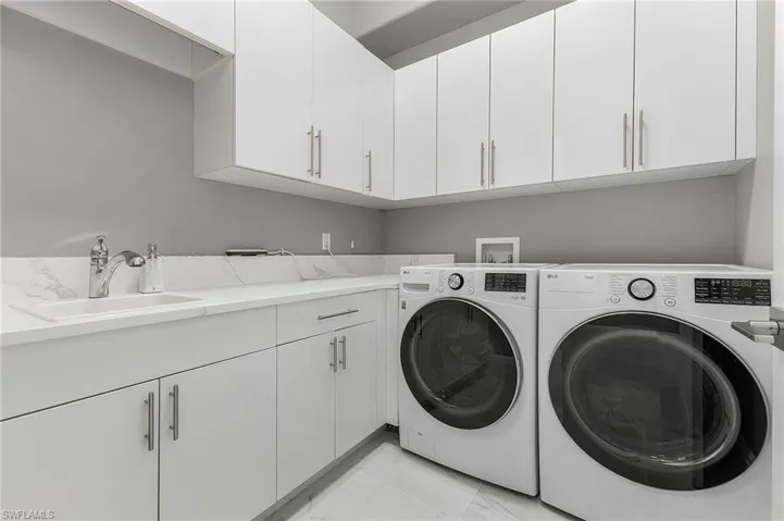 Laundry area featuring washer and dryer, cabinets, and sink