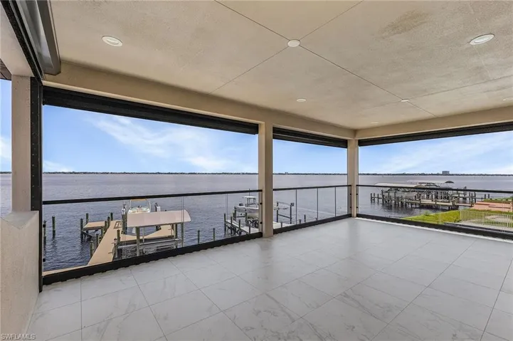 View of patio with a water view and a dock
