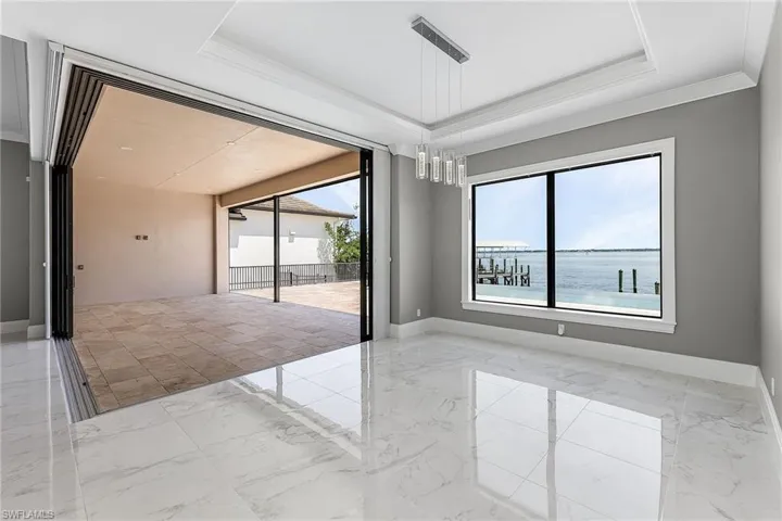 Empty room featuring a water view, ornamental molding, and a tray ceiling