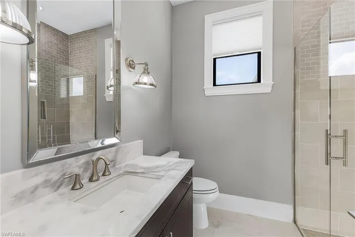 Bathroom featuring an enclosed shower, toilet, plenty of natural light, and vanity