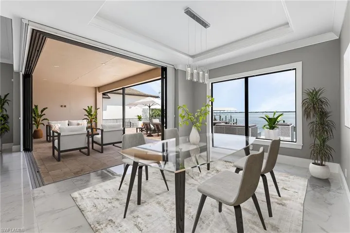 Dining area with a water view, a tray ceiling, and crown molding