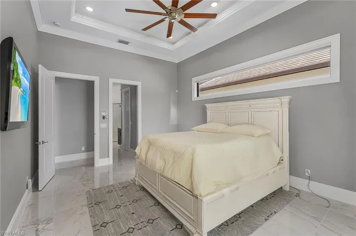 Bedroom featuring crown molding, ceiling fan, multiple windows, and a tray ceiling