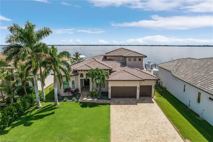 Mediterranean / spanish-style house with a water view, a garage, and a front lawn