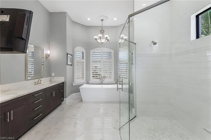 Bathroom featuring vanity, plus walk in shower, and an inviting chandelier