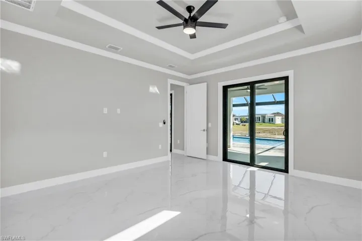 Spare room with ornamental molding, ceiling fan, and a tray ceiling