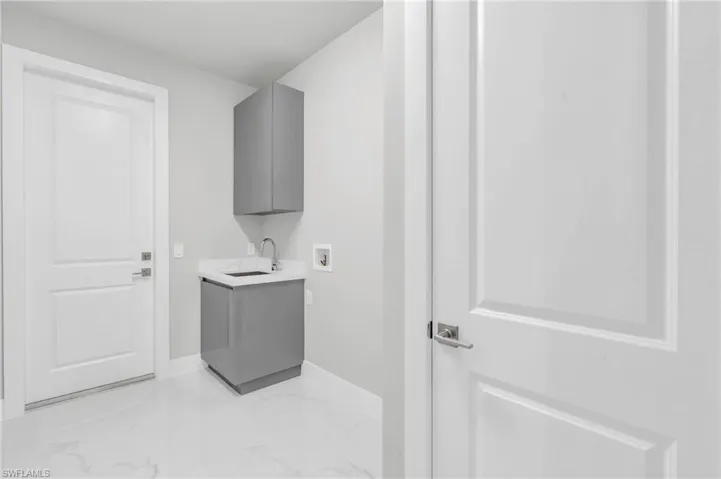 Laundry area with sink, hookup for a washing machine, and cabinets