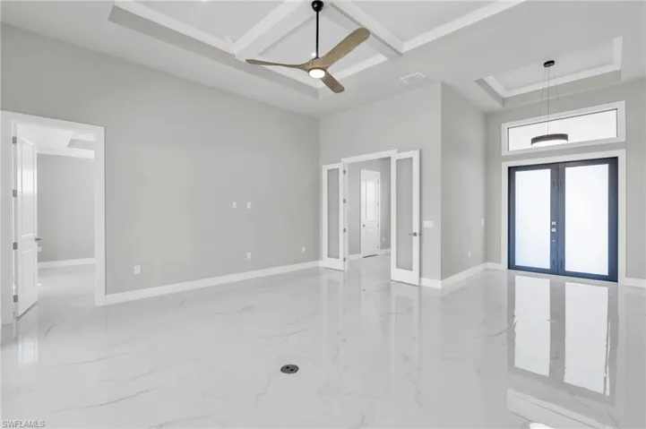 Foyer with ceiling fan, a towering ceiling, coffered ceiling, french doors, and a raised ceiling