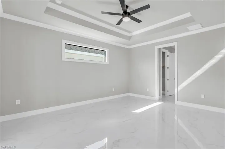 Spare room featuring a raised ceiling, ornamental molding, and ceiling fan