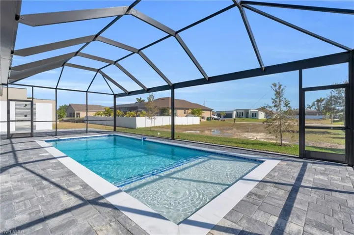 View of swimming pool featuring glass enclosure and a patio area