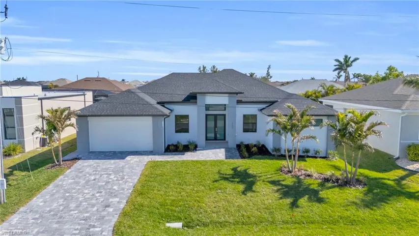View of front of property featuring a garage and a front lawn