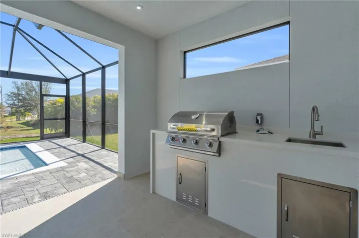 View of patio / terrace with an outdoor kitchen, sink, a lanai, grilling area, and a mountain view