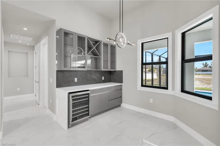Bar featuring decorative backsplash, gray cabinetry, wine cooler, and decorative light fixtures
