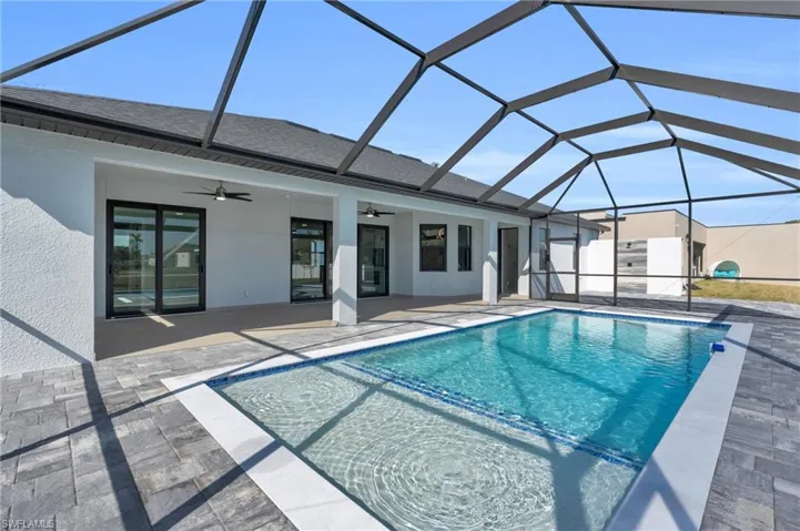 View of swimming pool with a patio area, ceiling fan, and glass enclosure