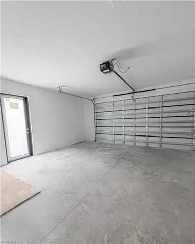 Spacious garage with a concrete floor, white painted walls, and an automatic garage door opener