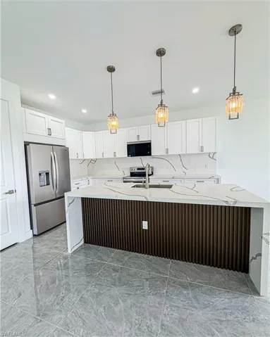 Modern kitchen featuring white cabinetry, stainless steel appliances, and a central island with a fluted wood-finish panel