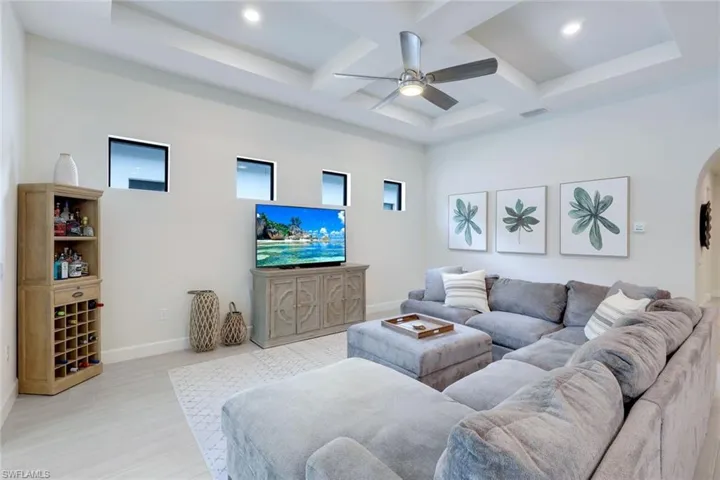 Living room with a high ceiling, coffered ceiling, ceiling fan, and beam ceiling