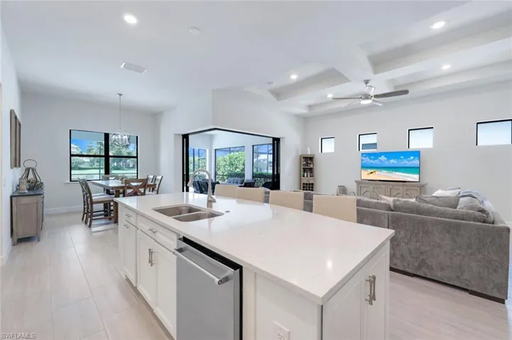 Kitchen featuring white cabinetry, coffered ceiling, ceiling fan, a center island with sink, and stainless steel dishwasher