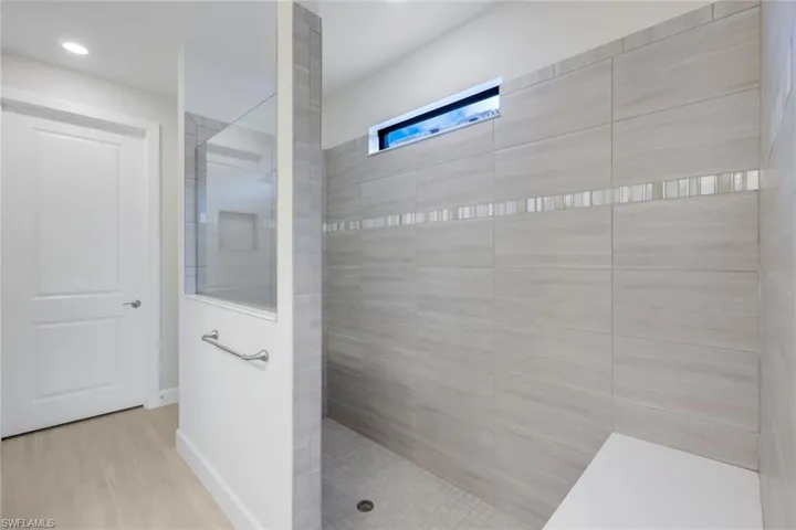 Bathroom with a tile shower and hardwood / wood-style flooring