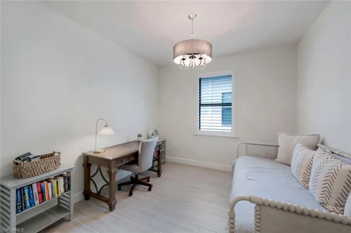 Office space with light hardwood / wood-style flooring and a chandelier