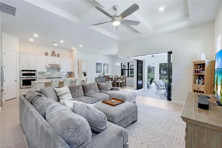 Living room featuring coffered ceiling, ceiling fan, and light hardwood / wood-style floors