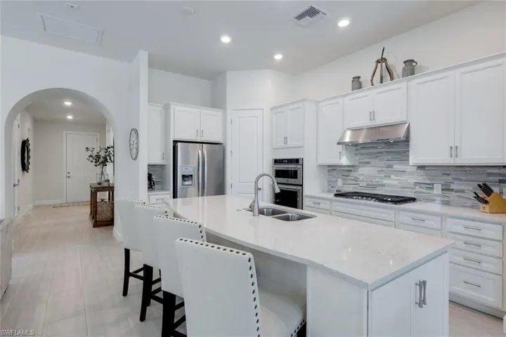 Kitchen featuring a center island with sink, sink, appliances with stainless steel finishes, and tasteful backsplash