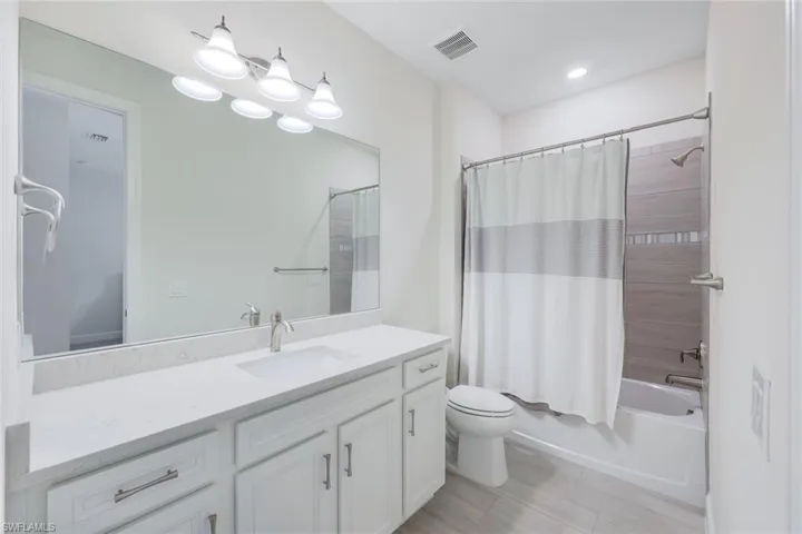 Full bathroom with shower / bathtub combination with curtain, vanity, toilet, and tile patterned flooring