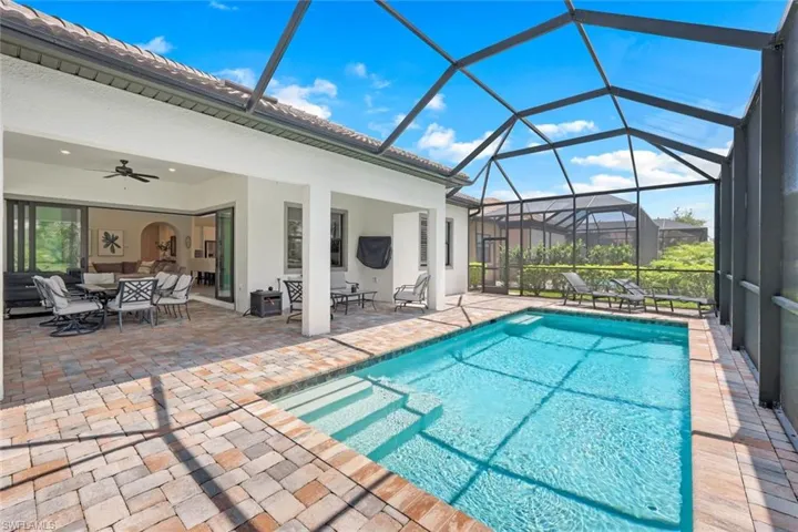 View of pool featuring ceiling fan, a patio area, glass enclosure, and an outdoor hangout area