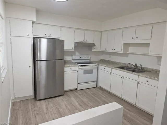 Kitchen with freestanding refrigerator, electric range, and white cabinetry