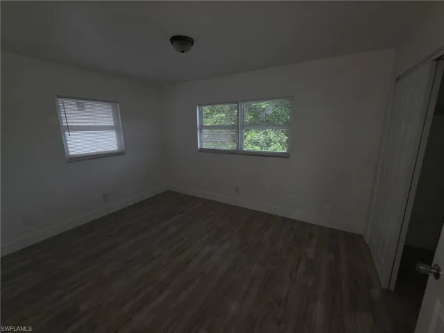 Unfurnished bedroom featuring a closet and dark wood-style flooring