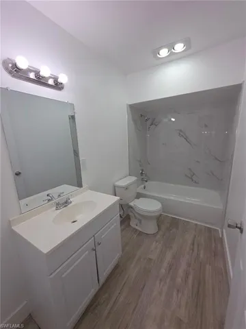 Bathroom featuring a combined bath / shower with marble appearance, vanity, light wood-type flooring, and recessed lighting