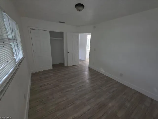 Unfurnished bedroom featuring dark wood-style flooring and a closet
