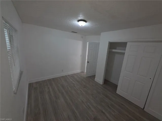 Unfurnished bedroom with a textured ceiling, wood finished floors, and a closet