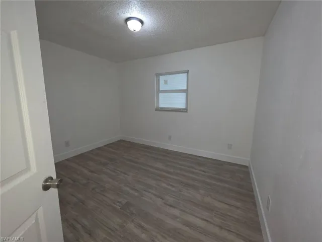 Unfurnished room featuring a textured ceiling and dark wood-style floors