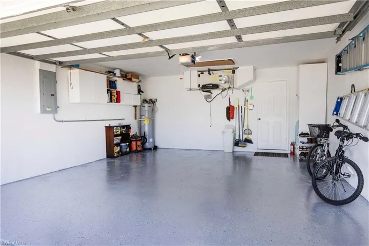 Garage with electric panel, water heater, and a garage door opener