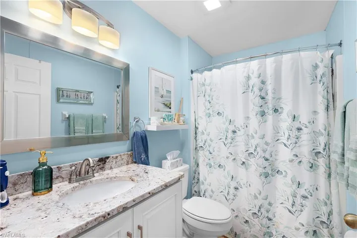 Bathroom featuring toilet, vanity, and walk in shower