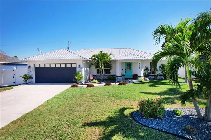 View of front of property featuring a garage and a front lawn