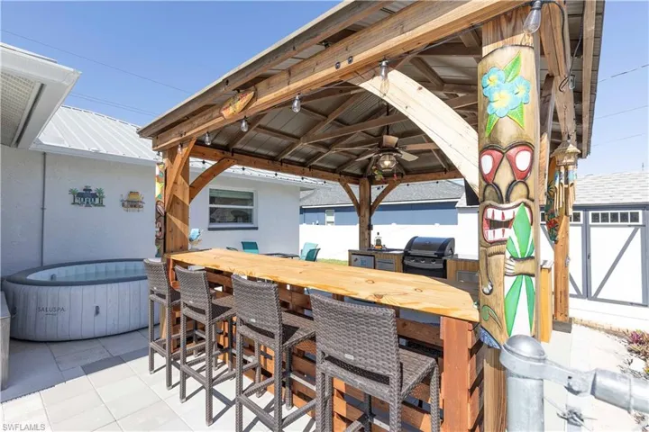 View of patio / terrace with grilling area, a gazebo, a bar, a hot tub, and ceiling fan