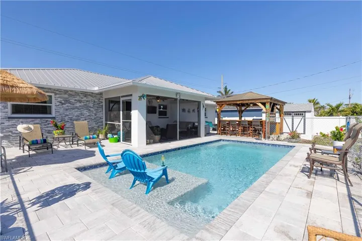 View of swimming pool featuring a patio, a sunroom, and a gazebo