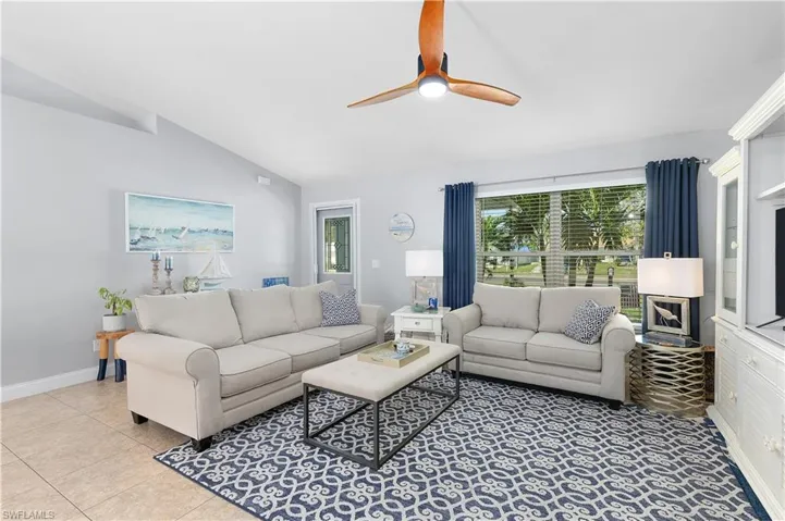 Living room with vaulted ceiling, ceiling fan, and light tile patterned floors