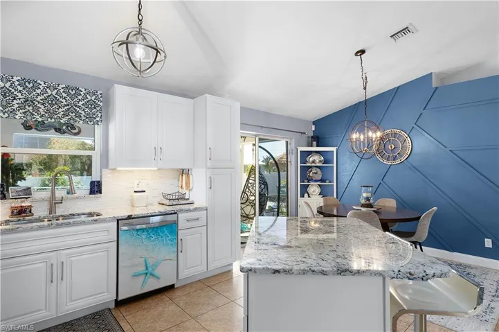 Kitchen featuring hanging light fixtures, dishwasher, white cabinets, and sink