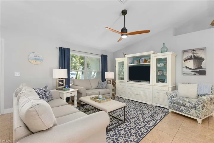 Tiled living room with ceiling fan and vaulted ceiling