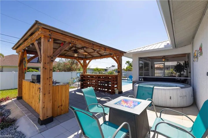 View of patio / terrace featuring exterior bar, ceiling fan, a gazebo, and a pool with hot tub