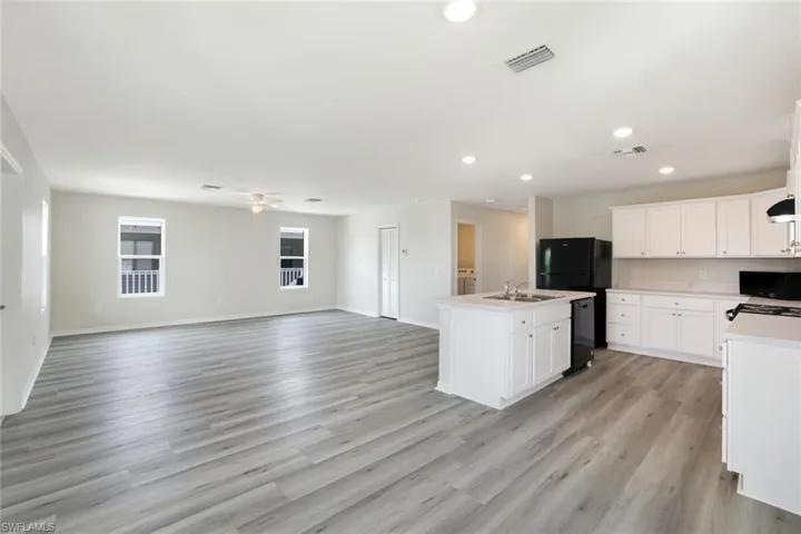 Kitchen with open floor plan, recessed lighting, light countertops, an island with sink, and ceiling fan