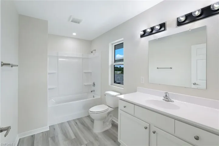 Bathroom with vanity, wood finished floors, and shower / tub combination