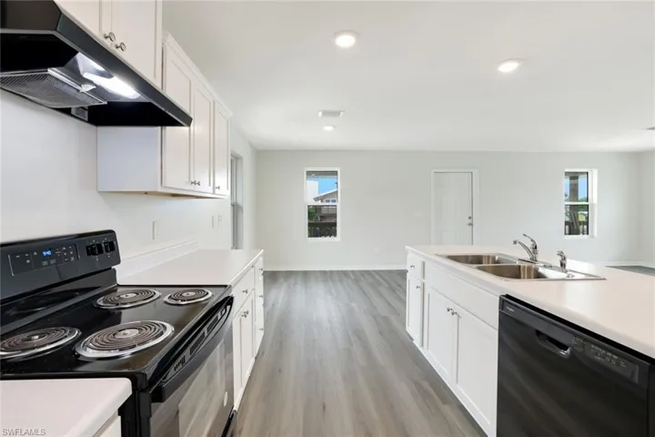 Kitchen with black appliances, under cabinet range hood, light countertops, white cabinets, and recessed lighting