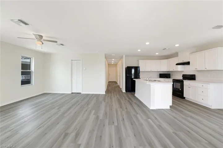 Kitchen with black appliances, open floor plan, light countertops, recessed lighting, and light wood-type flooring
