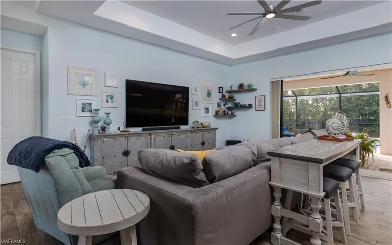 Living area featuring hardwood / wood-style floors, a ceiling fan, a raised ceiling, and recessed lighting