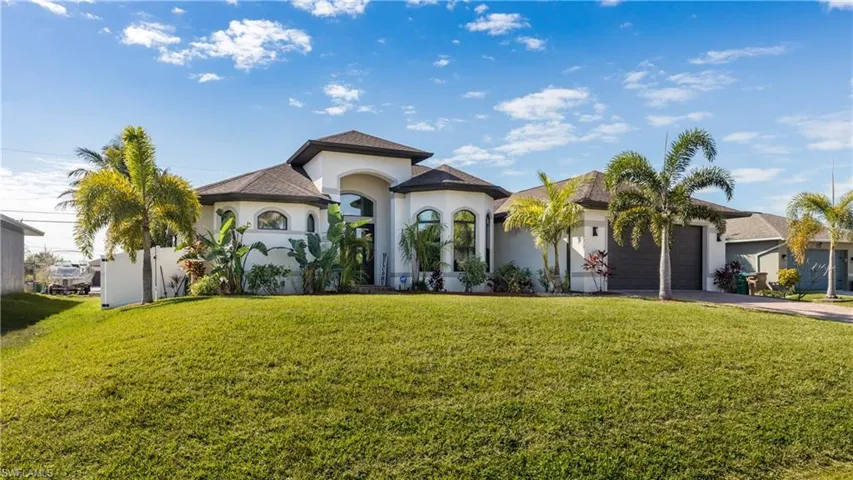 Mediterranean / spanish-style home featuring stucco siding, a front yard, an attached garage, and driveway